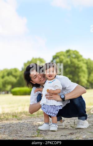 Vater und Tochter spielen im Schatten eines Baumes im Park Stockfoto