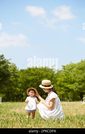 Mutter und Tochter tragen passende Hüte auf dem Gras Stockfoto