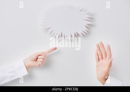 Gezackter Sprechballon und kämpfende Mann- und Frauenhände Stockfoto