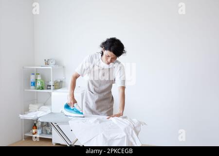 Mann bügelt in einem einfachen Zimmer Stockfoto