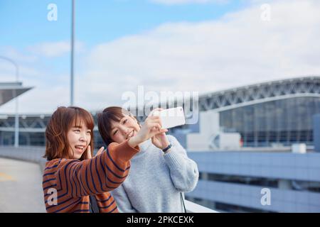 Zwei Frauen machen am Flughafen ein Selfie mit ihrem Smartphone Stockfoto