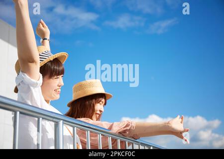 Zwei Frauen, die ihre Hände gegen den blauen Himmel strecken Stockfoto