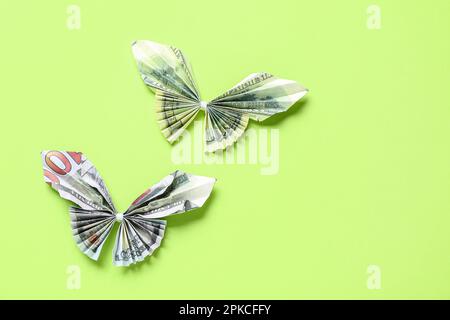 Origami-Schmetterlinge aus Dollar-Banknoten auf grünem Hintergrund Stockfoto