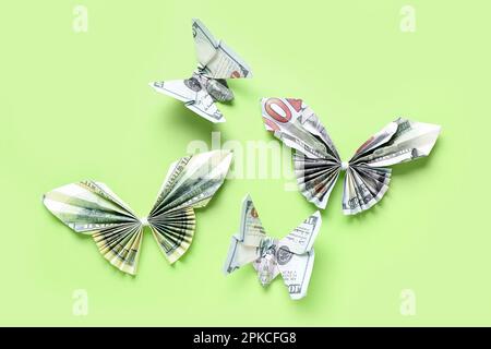 Origami-Schmetterlinge aus Dollar-Banknoten auf grünem Hintergrund Stockfoto