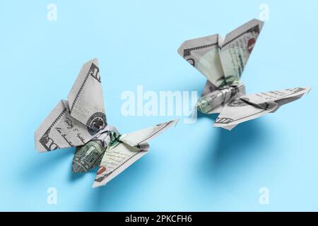 Origami-Schmetterlinge aus Dollar-Banknoten auf blauem Hintergrund, Nahaufnahme Stockfoto