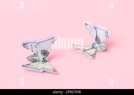 Origami-Schmetterlinge aus Dollar-Banknoten auf rosa Hintergrund, Nahaufnahme Stockfoto