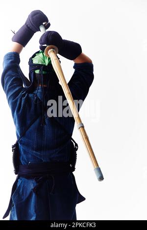 Rückansicht eines Mannes, der ein Kendo-Kleid trägt und ein Bambusschwert schwingt Stockfoto