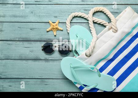 Flip-Flops mit Tasche, Sonnenbrille und Seesternen auf blauem Holzhintergrund Stockfoto