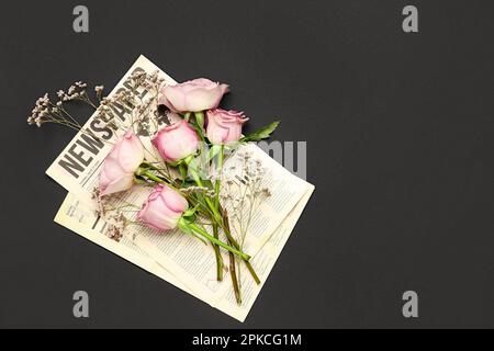 Rosa Rosen mit Zigeunern und Zeitungen auf schwarzem Hintergrund Stockfoto