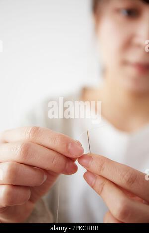 Frau eine Nadel einfädeln Stockfoto