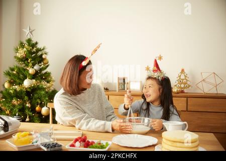 Ein Elternteil und ein Kind, die einen Weihnachtskuchen backen Stockfoto