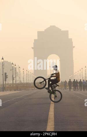 In The Misty Morning man, der einen Stunt auf dem Fahrrad vor dem India Gate vorführt, Neu-Delhi, Indien, Foggy Morning. Stockfoto
