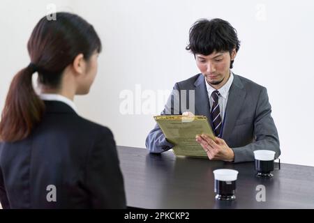 Ein männlicher Interviewer interviewt eine weibliche Jägerin und schreibt Informationen auf ein Dokument. Stockfoto