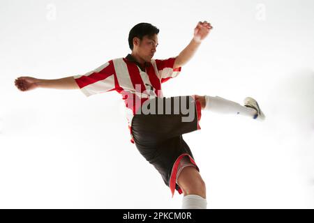 Ein Fußballspieler tritt einen Ball und schwingt sein Bein Stockfoto