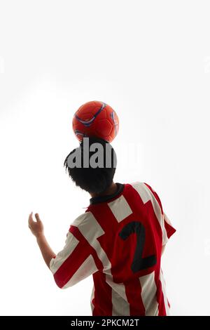 Fußballspieler balanciert den Ball auf der Stirn Stockfoto