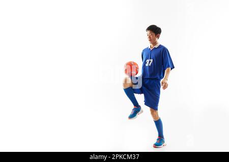 Ein Fußballspieler, der einen Ball hebt Stockfoto