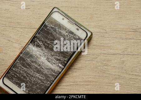 Mobiltelefon und zerbrochenes gehärtetes Glas auf isoliertem Hintergrund, Glasaustausch Stockfoto