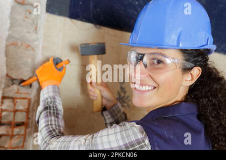 Frau hämmert einen Nagel in die Wand Stockfoto