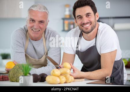 Hipster-Sohn mit seinem Senior-Vater, der in der Küche kocht Stockfoto