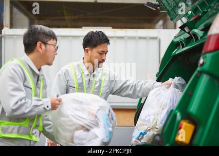 Männlicher Arbeiter mit einem Packwagen und Müllabfuhr Stockfoto