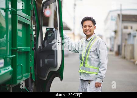 Männlicher Arbeiter mit Packer-Truck und lachend Stockfoto