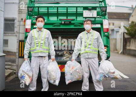 Ein männlicher Arbeiter mit einem Packwagen und Müllabfuhr Stockfoto