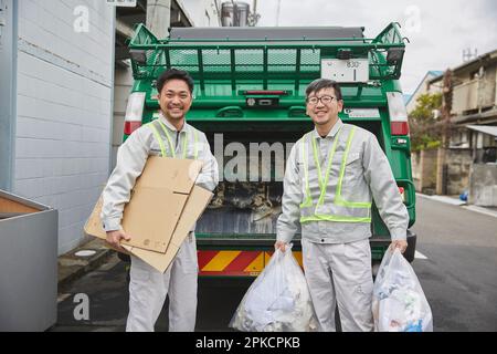 Männlicher Arbeiter mit Packwagen und Müll Stockfoto