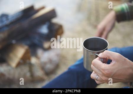 Die Hand eines Mannes, der eine Tasse im Camp hält Stockfoto