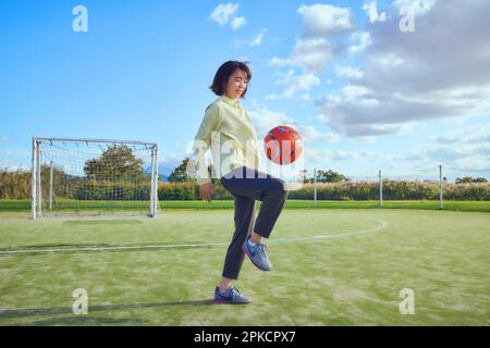 Eine Fußballspielerin hebt den Ball Stockfoto