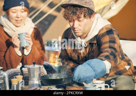 Mann und Frau, die auf dem Wintercampingplatz essen Stockfoto