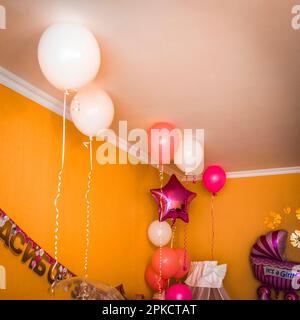 Das Bett des Mädchens in der Ecke des Zimmers ist mit Luftballons dekoriert. Stockfoto