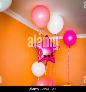 Das Bett des Mädchens in der Ecke des Zimmers ist mit Luftballons dekoriert. Stockfoto