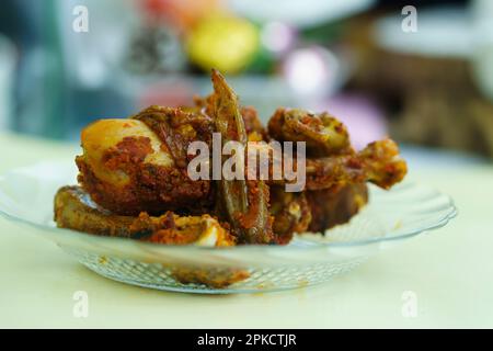 Gegrilltes Hähnchen mit würziger Marinierung, serviert auf einem durchsichtigen Teller auf dem Tisch. Bokeh-Hintergrund und selektiver Fokus. Stockfoto