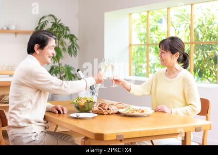 Ein Paar mittleren Alters, das an seinem freien Tag mit Champagner anstoßen Stockfoto