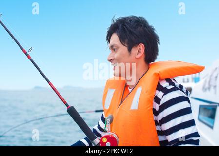 Ein Mann im Alter von 20s Jahren, der mit dem Boot im Meer angeln will Stockfoto