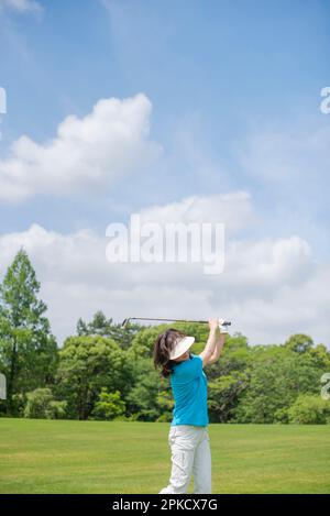 Eine Frau mittleren Alters, die Golf spielt Stockfoto