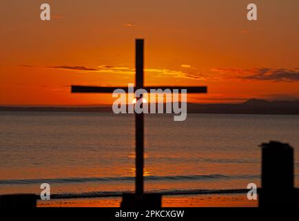 Portobello, Edinburgh, Schottland, Großbritannien. April 2023. Ein Kreuz, das am Sonnenaufgang vom Einheimischen Neil am Strand aufgestellt wurde, um den Osterfreitag zu feiern. Das Kreuz hat Ausschnitte aus dem alten und neuen Testament auf beiden Seiten. Stockfoto