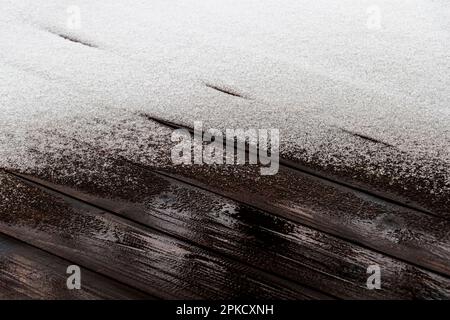 Schnee schmilzt auf dem Holzboden der offenen Veranda eines Privathauses. Stockfoto