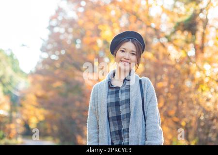 Eine Frau, die an einem Ort spaziert, während sie Herbstblätter sieht Stockfoto