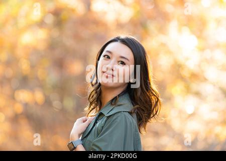 Eine Frau, die an einem Ort spaziert, während sie Herbstblätter sieht Stockfoto