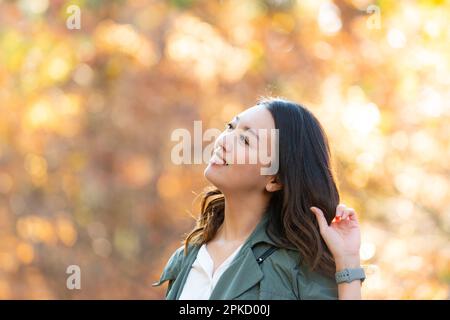 Eine Frau, die an einem Ort spaziert, während sie Herbstblätter sieht Stockfoto