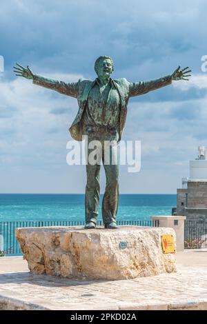 Bronzestatue des italienischen Sängers Domenico Modugno mit Blick auf die Altstadt auf den felsigen Klippen und dem blauen Meer mit offenen Armen wie dem berühmten Lied Volare Stockfoto