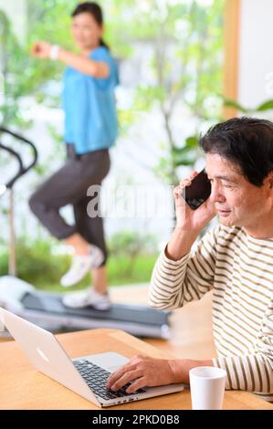 Telearbeit von Mann und Frau mittleren Alters mit einer Laufmaschine Stockfoto
