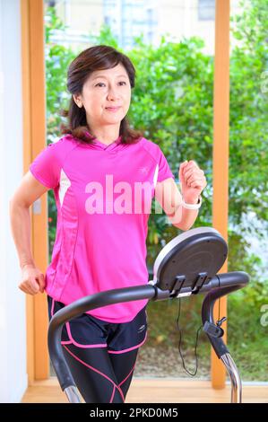 Eine Frau mittleren Alters, die zu Hause mit einer Maschine trainiert Stockfoto