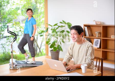 Telearbeit, Mann und Frau mittleren Alters, die Laufmaschine spielen Stockfoto