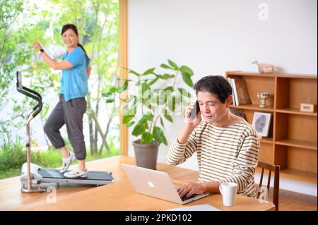Telearbeit, Mann und Frau mittleren Alters, die Laufmaschine spielen Stockfoto