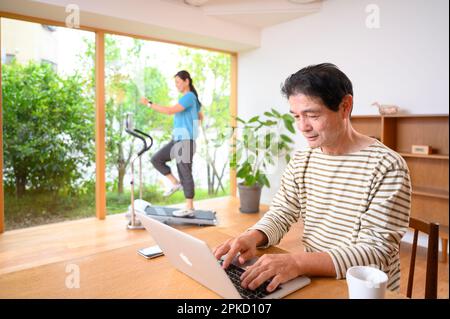 Telearbeit von Mann und Frau mittleren Alters mit einer Laufmaschine Stockfoto