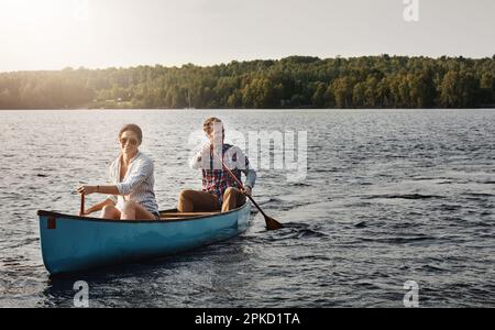 Genießen Sie die Schönheit des Sees mit dem Kanu. Ein junges Paar, das eine Kanufahrt auf dem See macht. Stockfoto