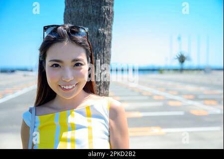 Eine Frau, die in ein Seebad reist und sich gegen eine Palme lehnt Stockfoto