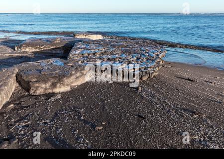 An der Sandküste der Ostsee lagen tagsüber und im Winter schmelzende Eisschollen Stockfoto